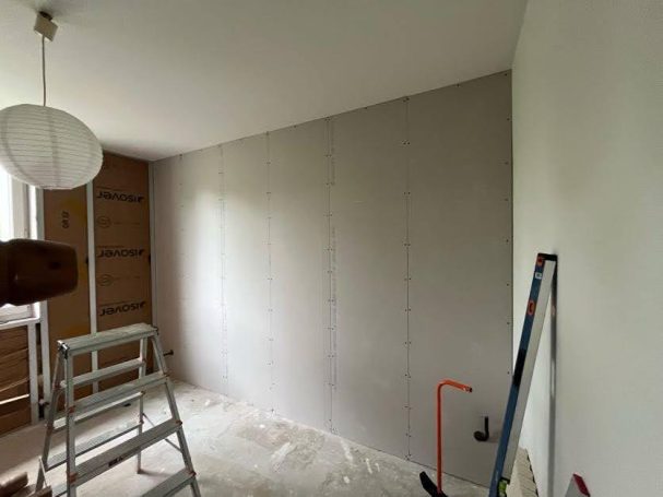 Isolation et plaquage en cours des murs ouest et sud de la chambre 1